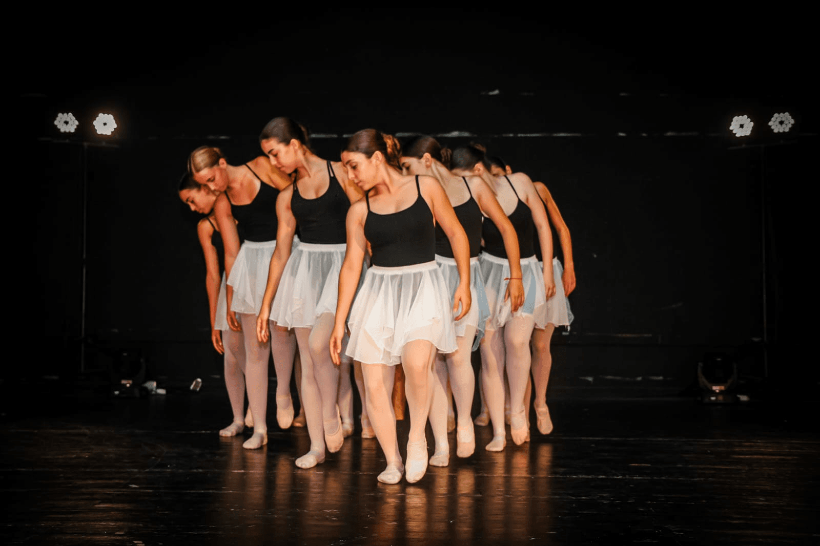 Ballet dancers in white tutus performing coordinated line formation